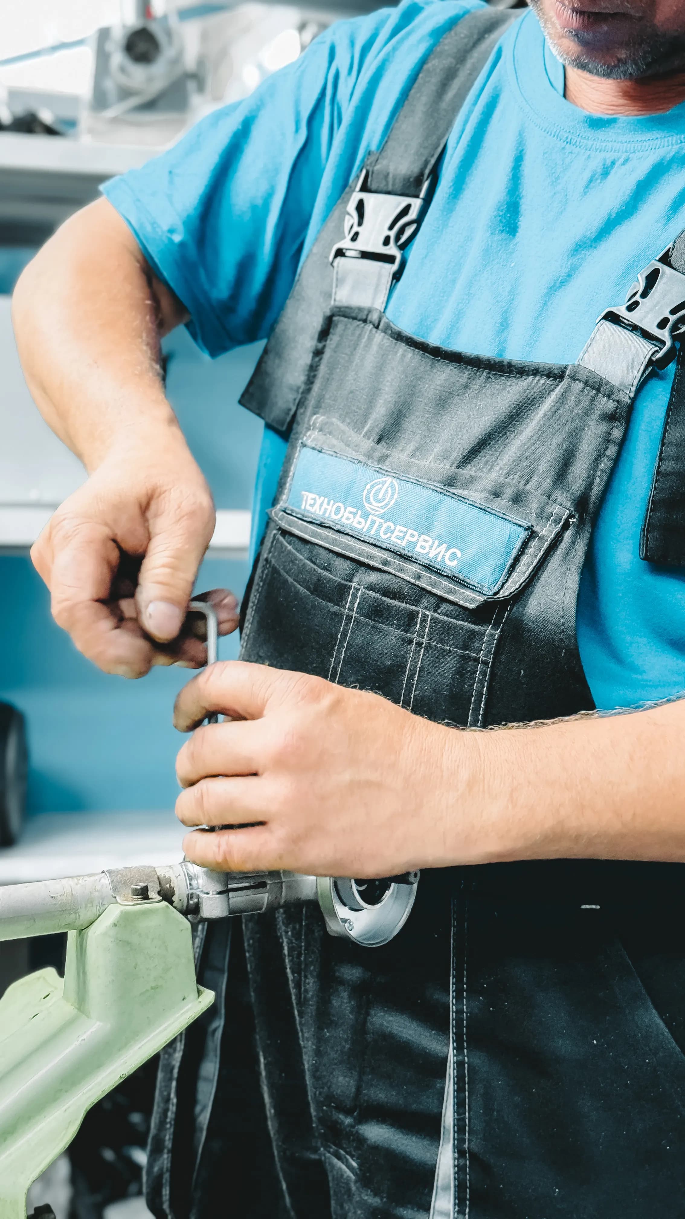 Plumber in a blue uniform repairing a pipe with a wrench