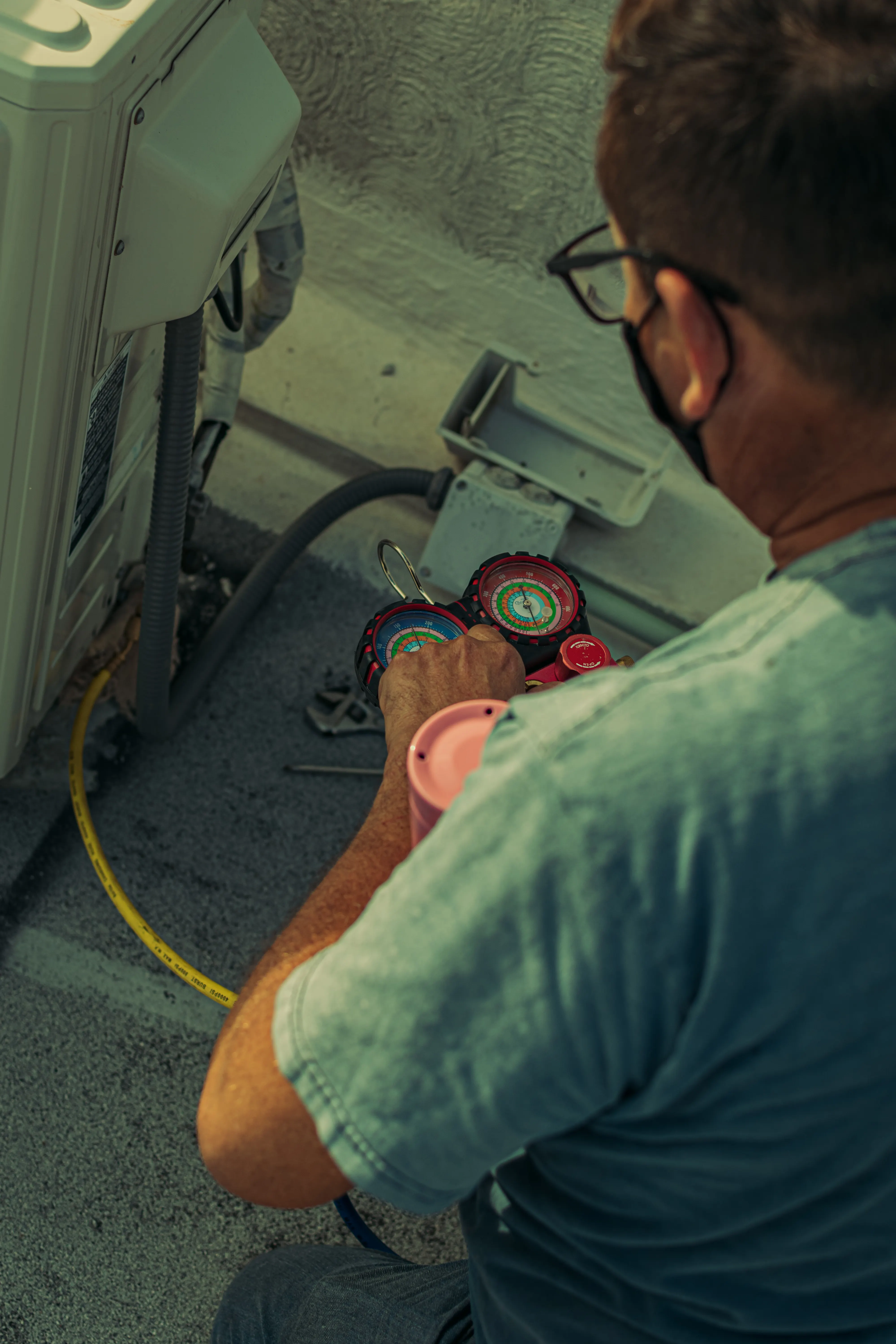 Close-up of a technician's hands on a refrigerant manifold gauge